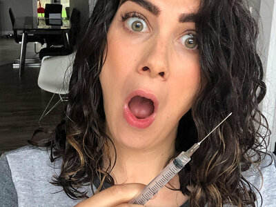 fertility warrior amy baker making a funny face while holding an ivf needle, 